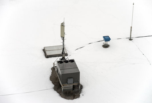 Roof of a commercial building with a external units of the commercial air conditioning and ventilation systems, cellular antenna and lightning rod. Winter photo.