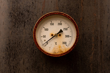 Old rusty water thermometer on black metal background