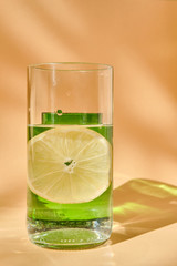 Glass of water with lemon and a green glass. Play of light