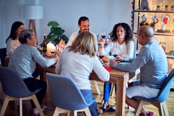 Family and friends dining at home celebrating christmas eve with traditional food and decoration, all sitting on the table together