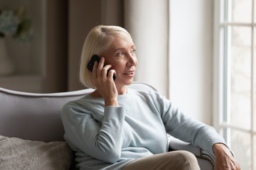 Happy grandmother talking with grandchildren via smartphone at home.