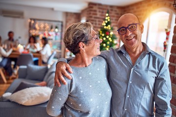Family and friends dining at home celebrating christmas eve with traditional food and decoration, romantic senior couple hugging in love
