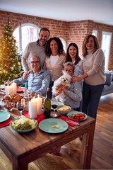 Family and friends dining at home celebrating christmas eve with traditional food and decoration, taking picture all together