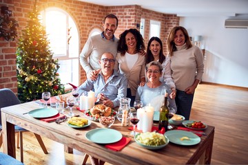 Family and friends dining at home celebrating christmas eve with traditional food and decoration, taking picture all together