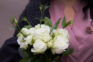 Close-up female hands holding a bouquet of white alstroemeria, selective focus