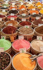 many vessels filled with spices in various colors are offered from an oriental bazaar