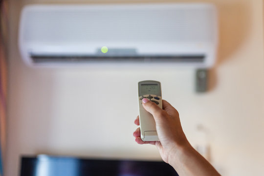 In female hands of the remote control air conditioning in the hotel room. Cooling and airing in the hotel room. Close-up view of the use of some electrical appliances such as air conditioning.