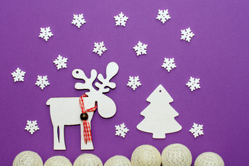 Christmas creative flat handmade picture on top of white cardboard with a deer, Christmas tree and snow on a purple background.