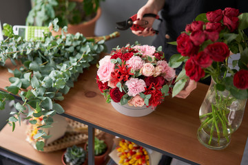 Floral shop concept . Florist woman creates flower arrangement in a round box. Beautiful bouquet of mixed flowers. Handsome fresh bunch. Flowers delivery