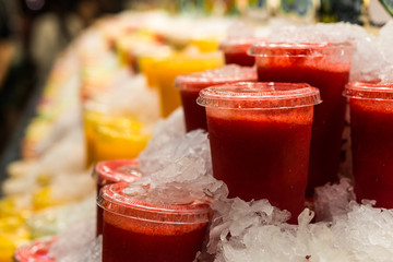 A variety of different colorful fruit smoothies at the farmers market stall