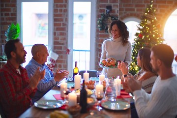 Beautiful family smiling happy and confident. Showing roasted turkey and applauding celebrating Christmas at home