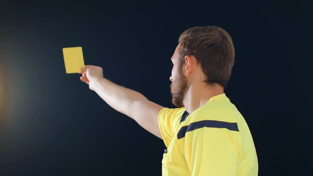 Football Soccer referee on black background showing penalty yellow card, 4k slow motion
