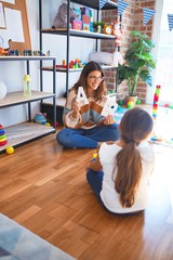 Beautiful teacher teaching  toddler  alphabet around lots of toys at kindergarten