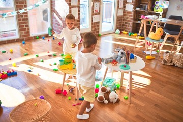 Adorable blonde twins playing around lots of toys. Cooking plastic food toy at kindergarten