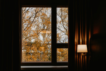 View throught retro hotel's window on Autumn trees. Creative art photography.