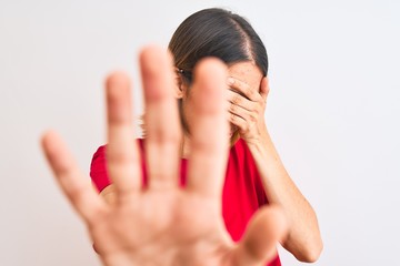 Beautiful redhead woman wearing casual red t-shirt over isolated background covering eyes with hands and doing stop gesture with sad and fear expression. Embarrassed and negative concept.