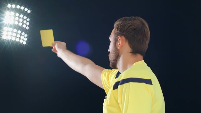 Football Soccer referee on black background showing penalty yellow card, 4k