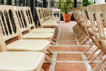 Many empty white wooden chairs lined up for a retro style event.