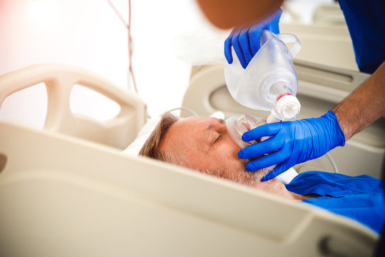 Doctors putting an oxygen mask on patient in hospital. First aid help. Reanimation room. Uncontious patient.