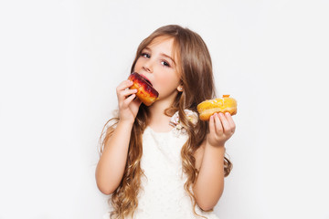 Little happy cute girl is eating donuts on white background isolated. Child is having fun with donut. Tasty sweet food for kids. Free space for text mockup