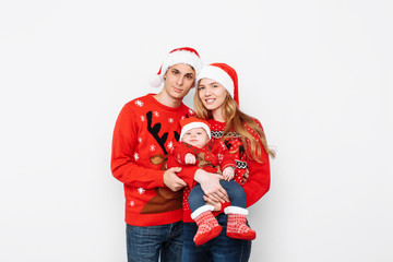 Happy family in Santa hats, mom dad and little baby celebrate Christmas