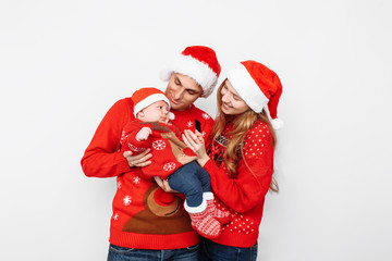 Obraz premium Happy family in Santa hats, mom dad and little baby celebrate Christmas