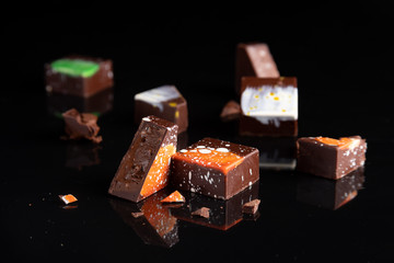 Art colorful chocolate candies on black background, selected focus