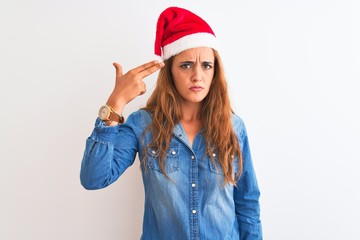Young beautiful redhead woman wearing christmas hat over isolated background Shooting and killing oneself pointing hand and fingers to head like gun, suicide gesture.