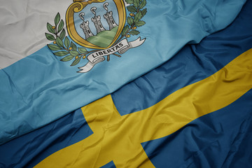 waving colorful flag of sweden and national flag of san marino.