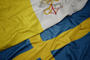 waving colorful flag of sweden and national flag of vatican city.