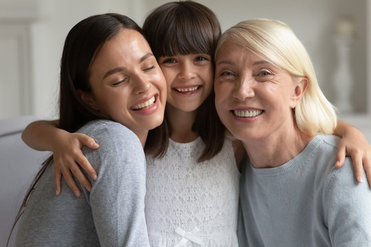 Happy adorable little girl hugging smiling mother and mature granny.