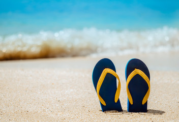 Flip flops on the white sand beach with blue sea background