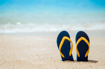 Flip flops on the white sand beach with blue sea background