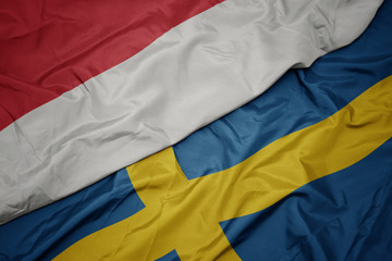 waving colorful flag of sweden and national flag of indonesia.