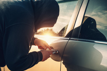 Car robber or thief trying to break auto door lock, close up. Car theft concept