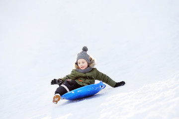 Fototapeta na wymiar Little boy enjoy riding on ice slide in winter.