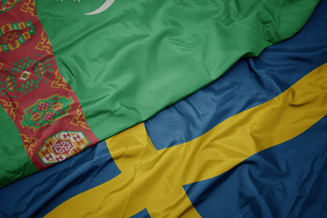 waving colorful flag of sweden and national flag of turkmenistan.
