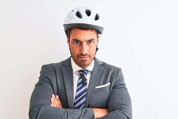 Young handsome business man bike helmet and wireless earphones over isolated background skeptic and nervous, disapproving expression on face with crossed arms. Negative person.