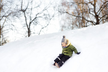 Fototapeta na wymiar Little boy enjoying riding on ice slide in winter.