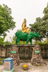 Bang Saen, Thailand - March 16, 2019: Wang Saensuk Buddhist Monastery. Colorful statues of sitting Chinese God, Lie Lu-Oew Koong in gold sitting on green bull, is god of past good deeds.