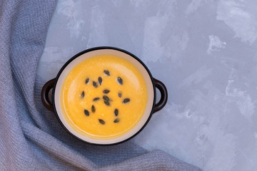 Bowl of pumpkin cream soup on concrete grey background