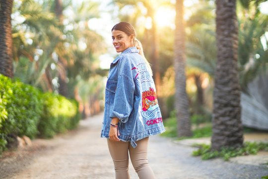 Young beautiful woman wearing denim jacket smiling happy and confident. Standing with smile on face at the town park
