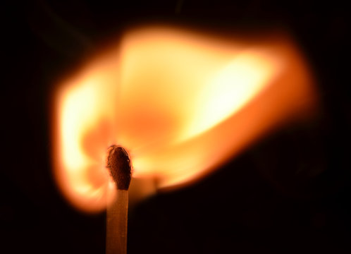 Burning match on black background
