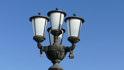 Fototapeta na wymiar Lampione stradale sul lungomare di Bari, con lucchetti appesi come simboli d'amore