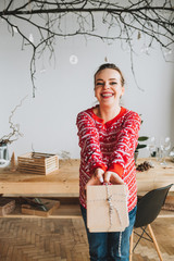 Happy pregnant woman smiling happily and holding a gift wrapped in plain paper