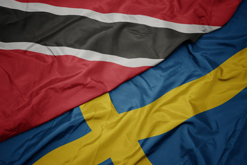waving colorful flag of sweden and national flag of trinidad and tobago.