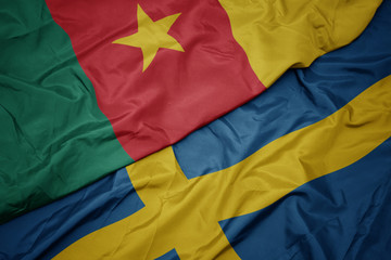 waving colorful flag of sweden and national flag of cameroon.