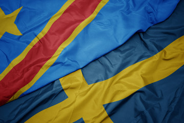 waving colorful flag of sweden and national flag of democratic republic of the congo.
