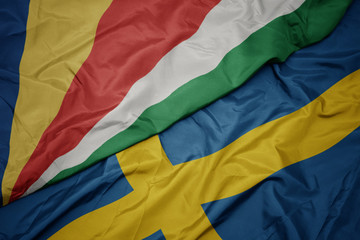 waving colorful flag of sweden and national flag of seychelles.
