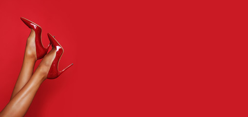 Beautiful long legs in red high heels with a copy space in the background.